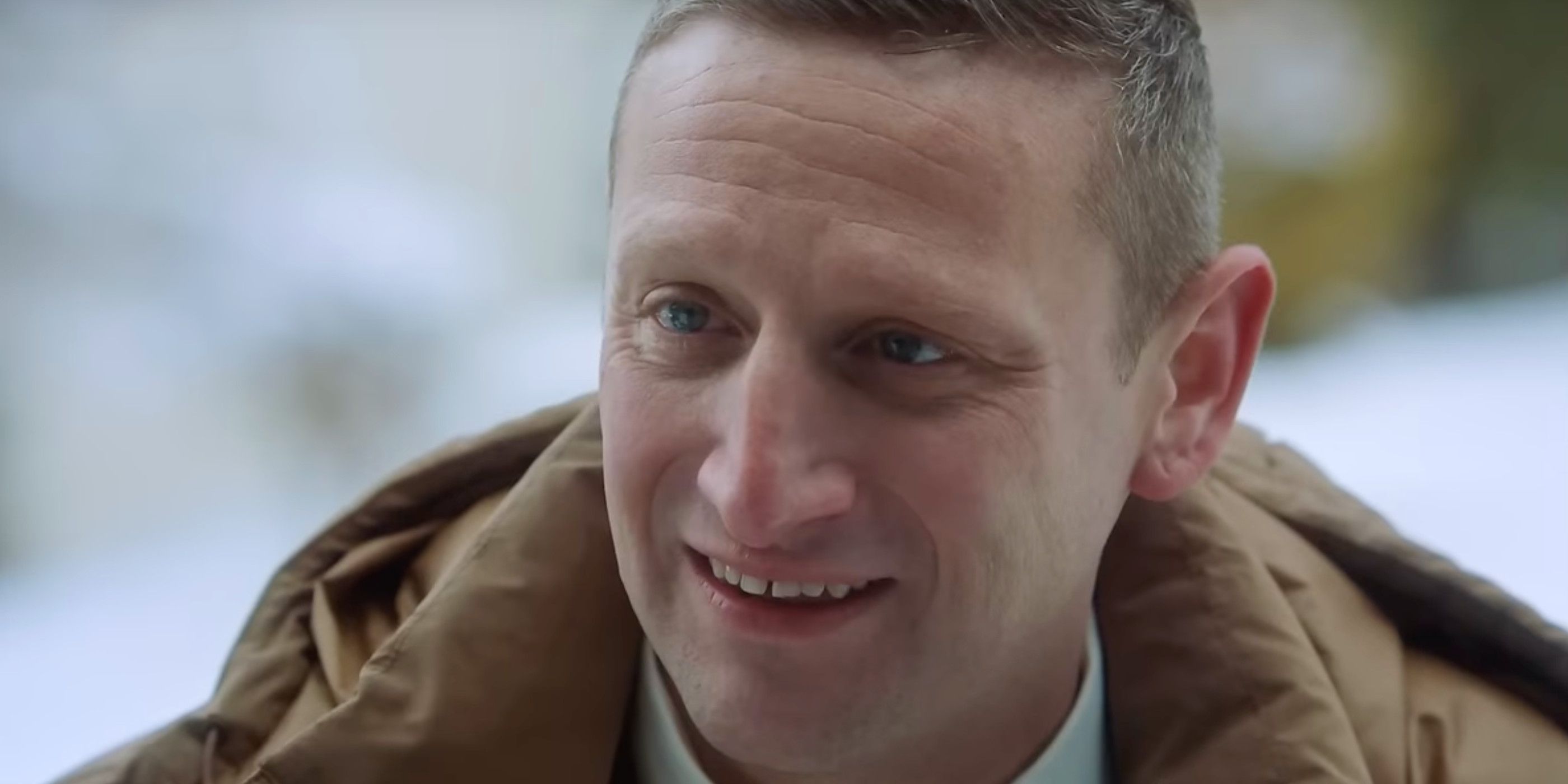 Tim Robinson smiling while wearing a brown coat in a close up in Friendship