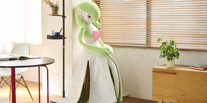 life-sized gardevoir pokemon plush next to a window leaned against a wall