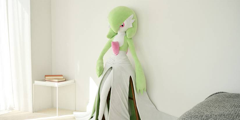 life-sized gardevoir pokemon plush leaning against a wall in a bedroom