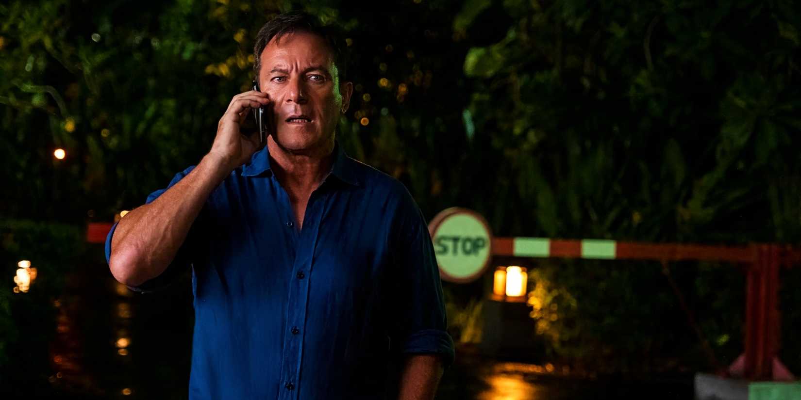 Jason Isaacs looks stressed while talking on the phone outside of the hotel in The White Lotus season 3