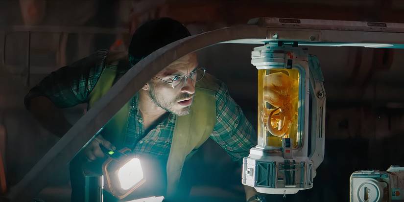 Jonathan Bailey aims a flashlight at a dinosaur specimen in Jurassic World Rebirth