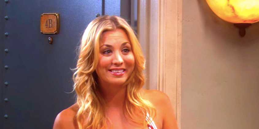 Kaley Cuoco's Penny smiles standing at her apartment door from The Big Bang Theory