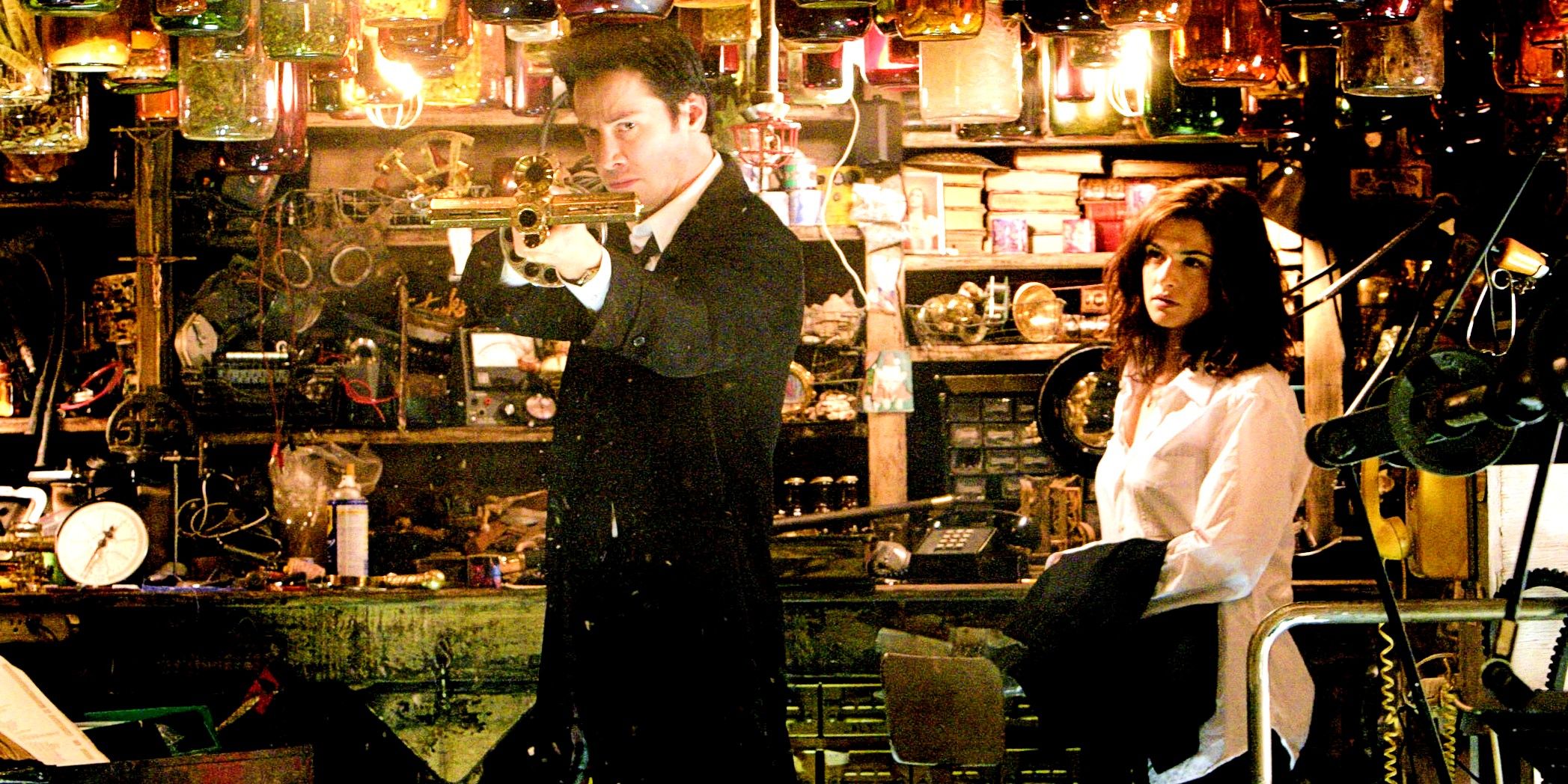 Keanu Reeves As John Constantine Holding A Weapon In A Cluttered Shop In Constantine Movie