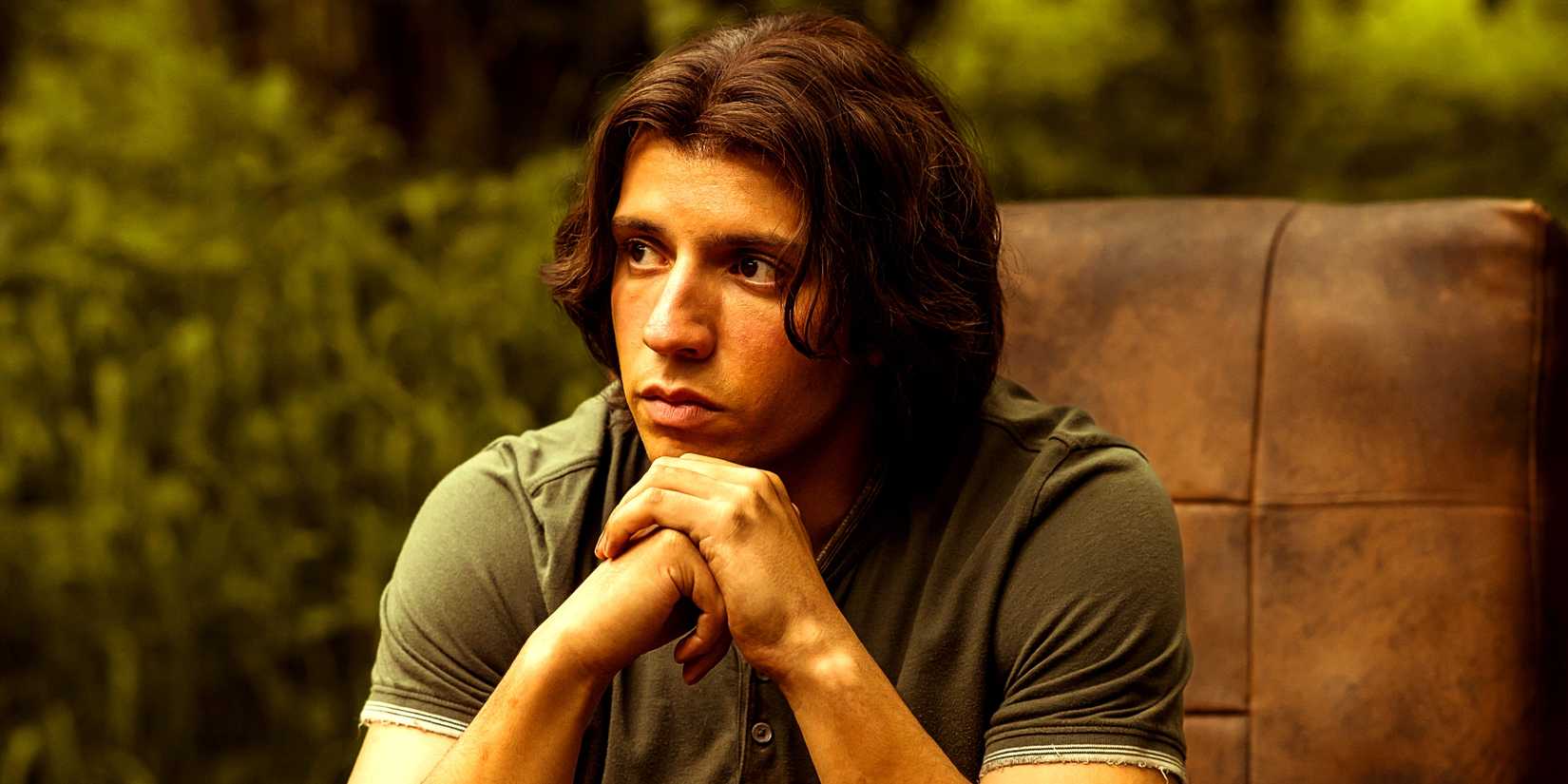 Kevin Alves as Teen Travis sitting on a chair contemplating in the wilderness in Yellowjackets season 3 episode 3