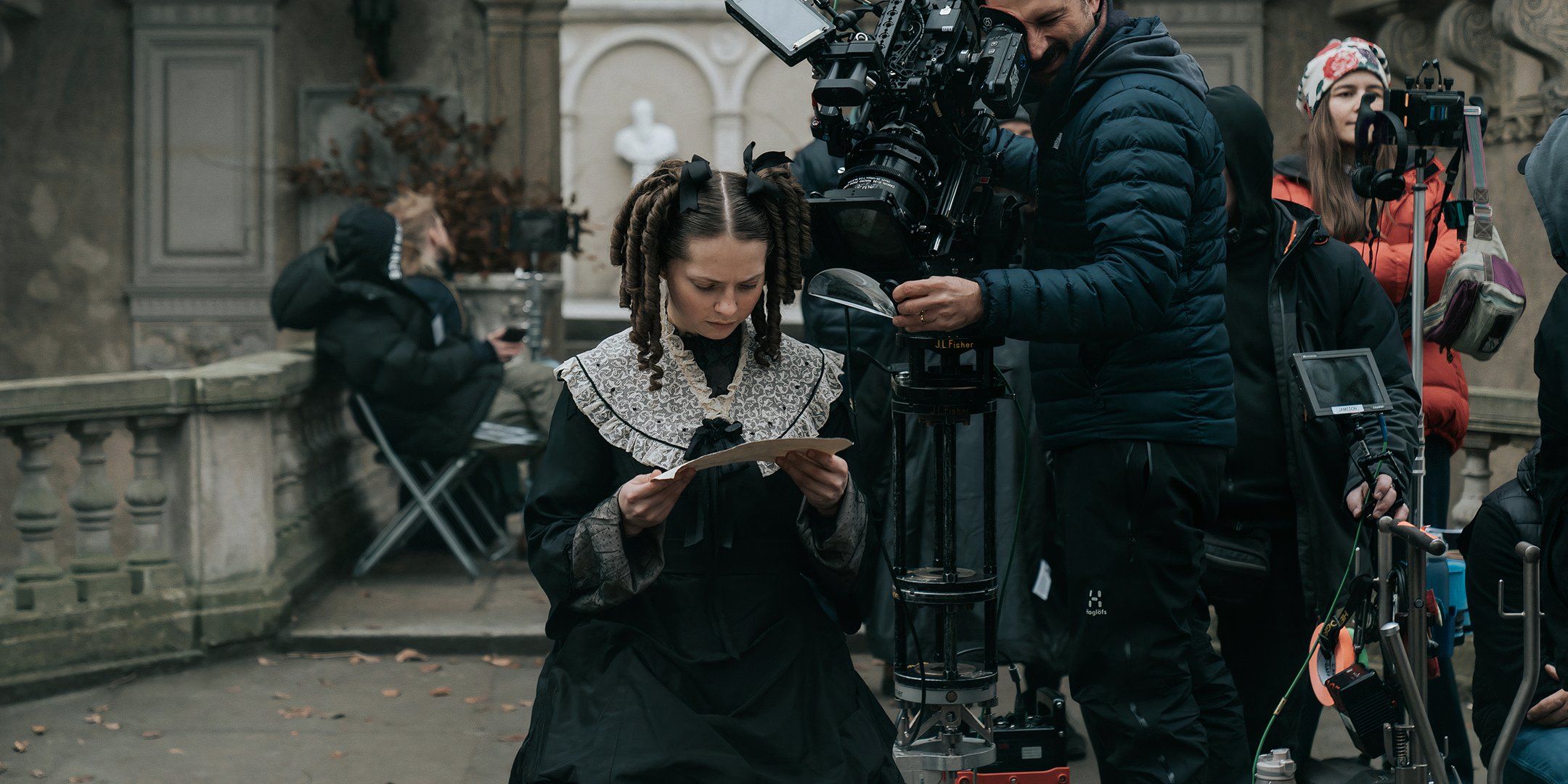 Lea Myren as Elvira reading a piece of paper with a cameraman over her shoulder on The Ugly Stepsister set