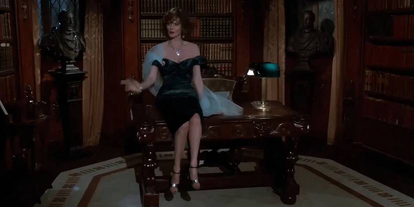 Lesley Ann Warren as Miss Scarlet sitting on a table in Clue