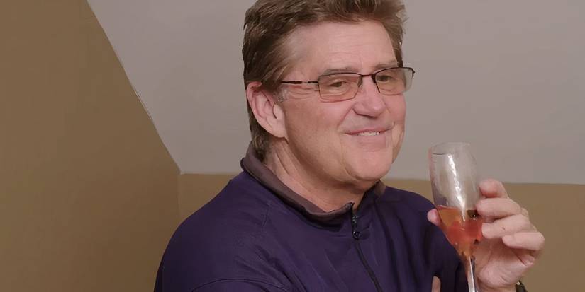 Mark Bessette In 90 Day Fiance in blue shirt holding champagne glass smiling