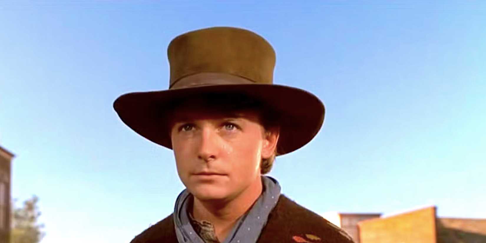 Michael J Fox's Marty McFly stands in the street dressed as Clint Eastwood in Back to the Future Part III