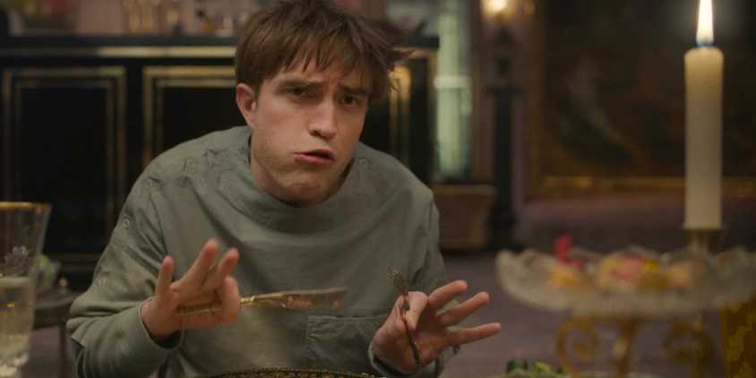 Mickey 17 (Robert Pattinson) making a funny face while having dinner in Mickey 17