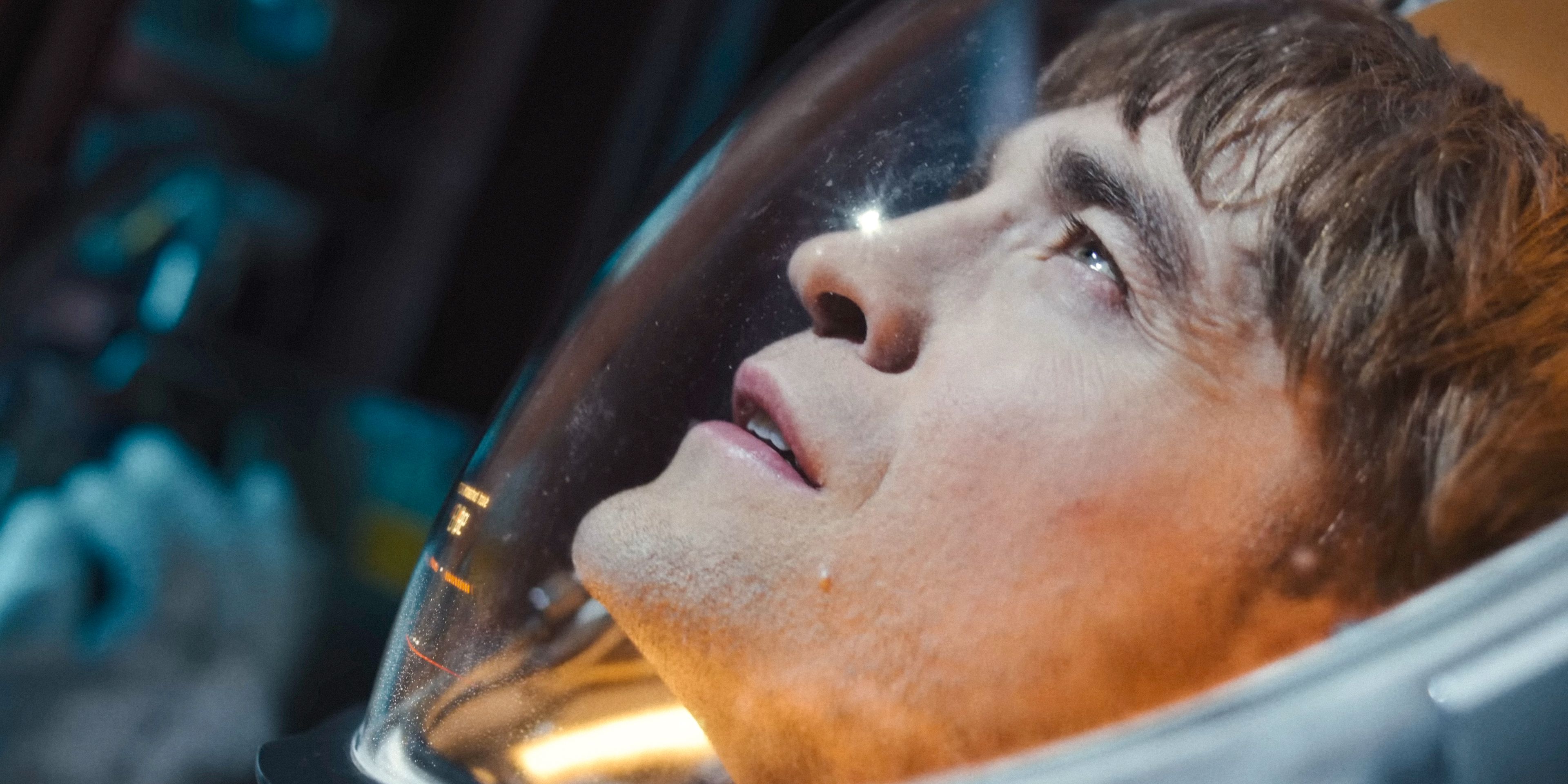 Mickey (Robert Pattinson) wearing an astronaut helmet, gazing into space in Mickey 17