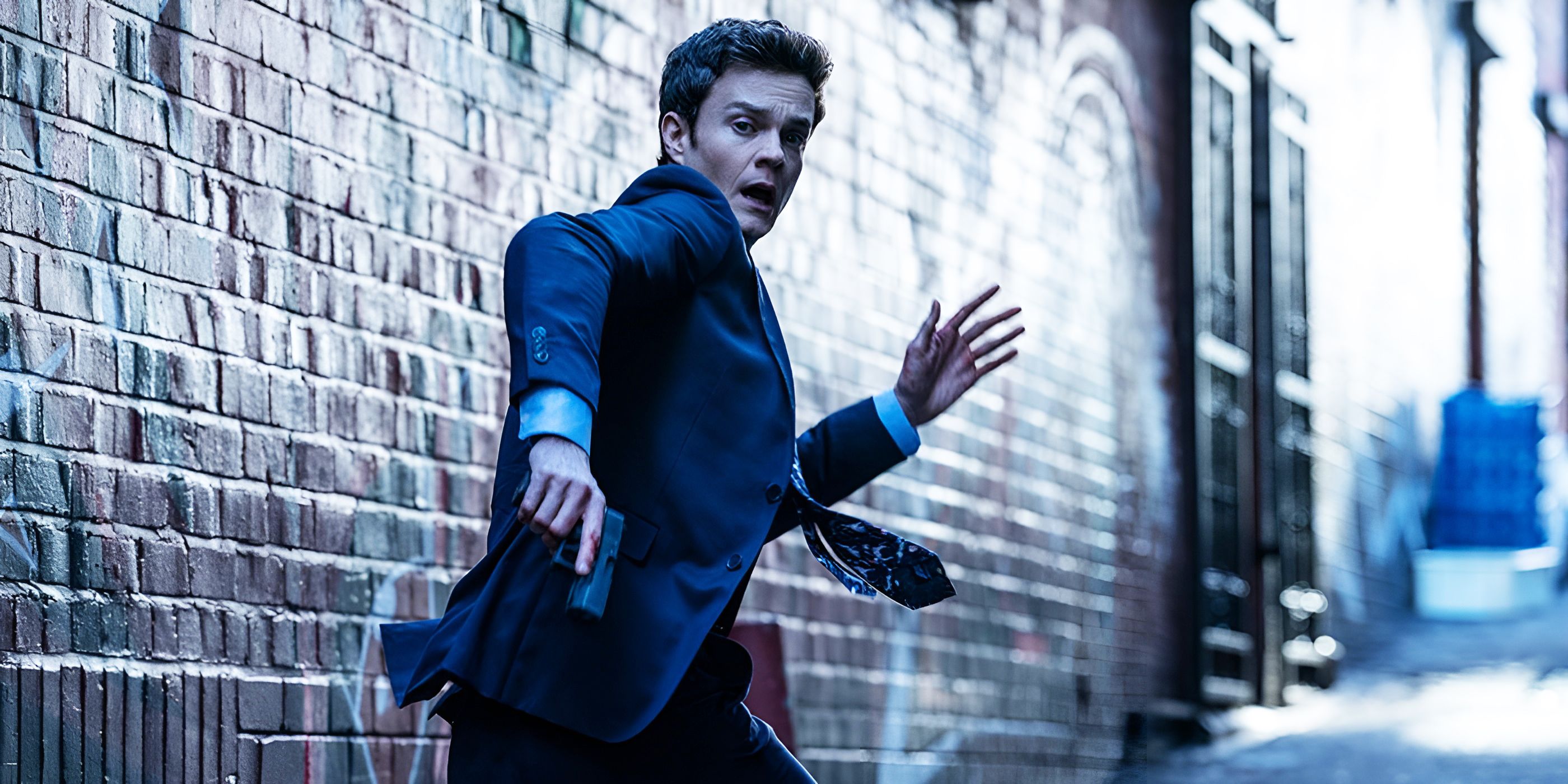 Novocaine Jack Quaid as Nathan Caine running scared with a gun