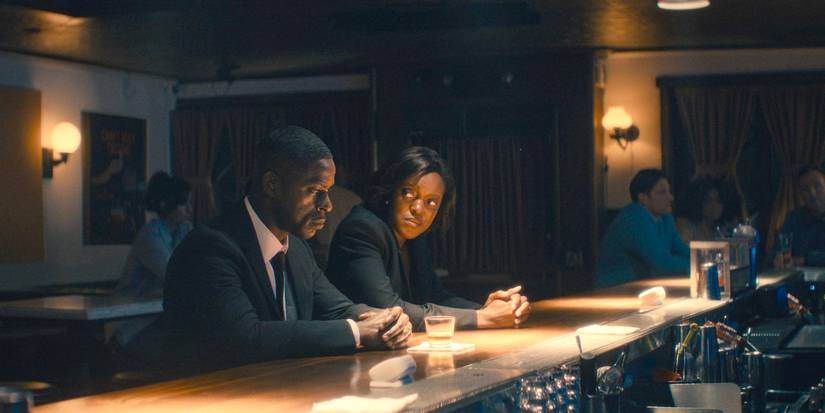 Xavier (Sterling K. Brown) and Robinson (Krys Marshall) sit in a bar, lost in thought about the deaths of Cal and Billy in Paradise (2025) Season 1 Ep 5