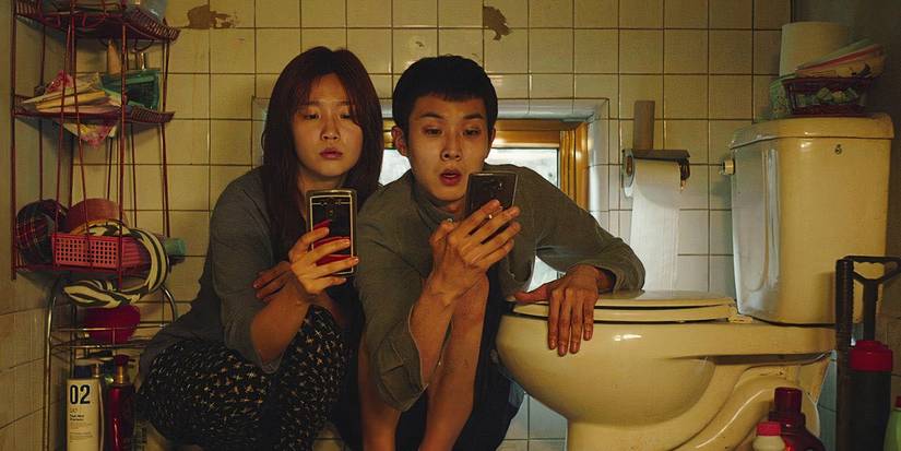 Two characters on their phones in the bathroom in Parasite.