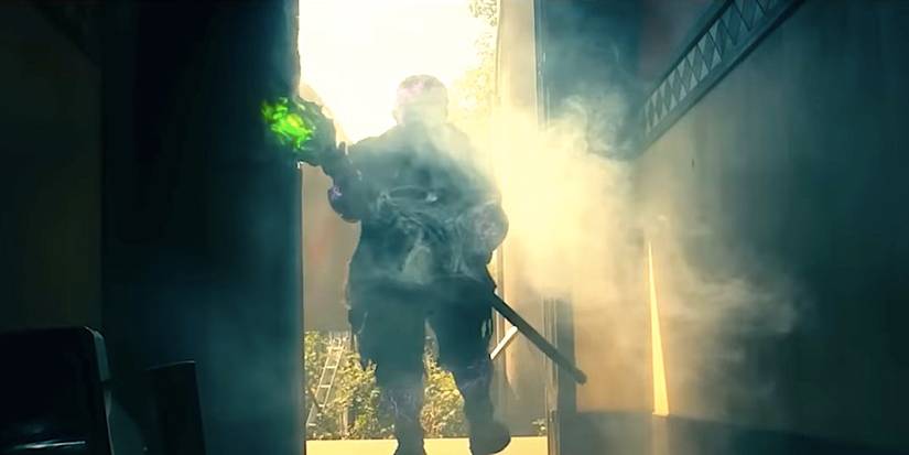 Peter Dinklage's Toxic Avenger stands in a doorway wielding a mop in The Toxic Avenger 2025