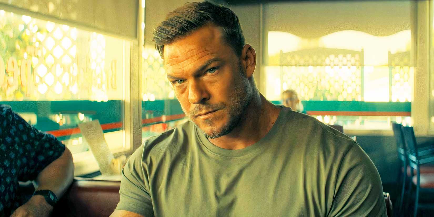 Alan Ritchson looking serious as Reacher while in a diner in Reacher season 3