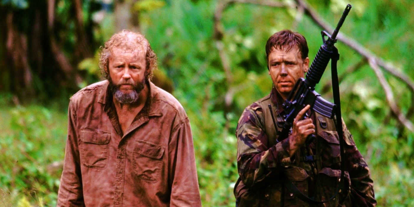 Russell Crowe holding a rifle in Proof of Life alongside David Morse