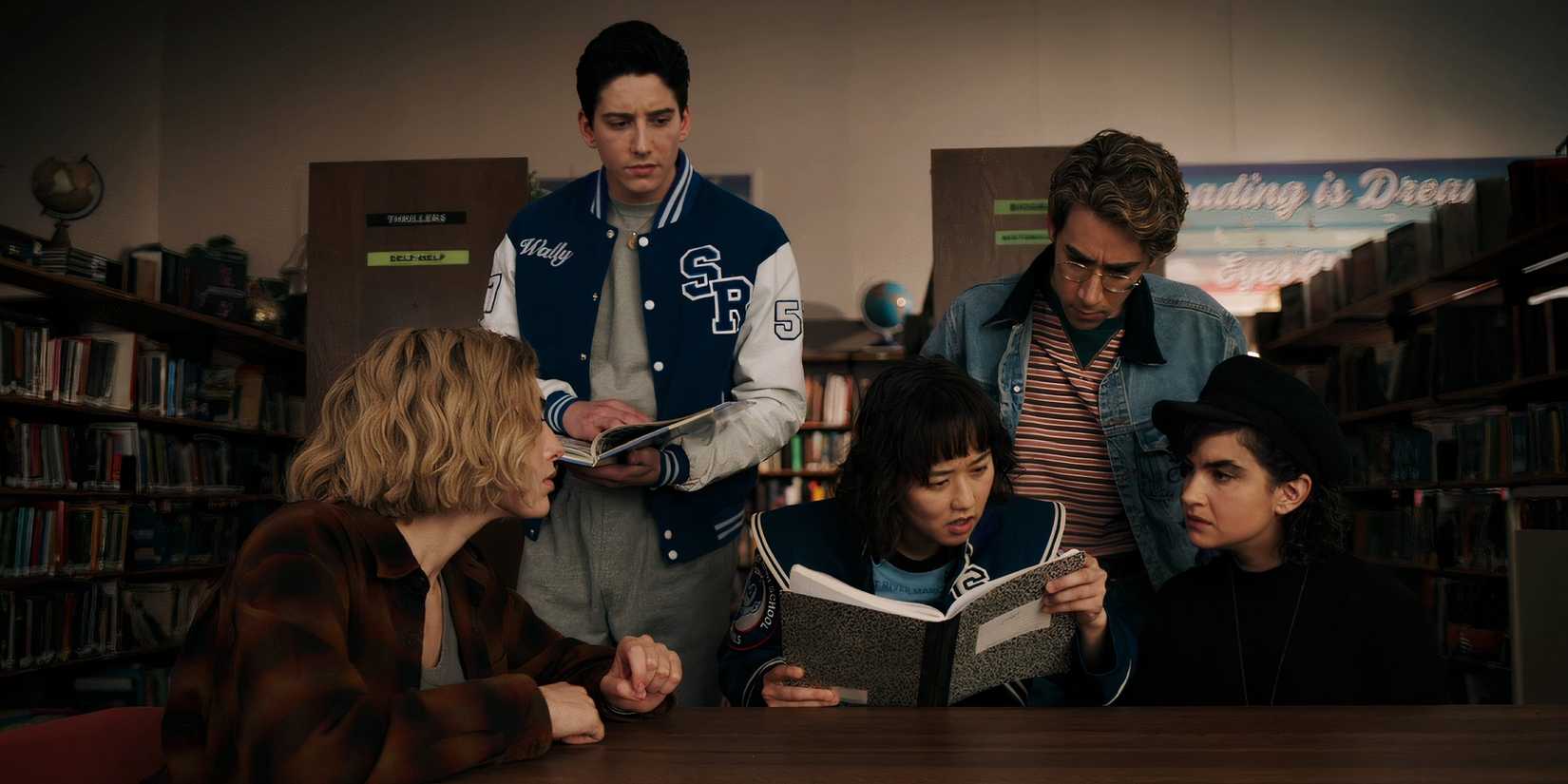 The characters of School Spirits investigate Janet's notebook.