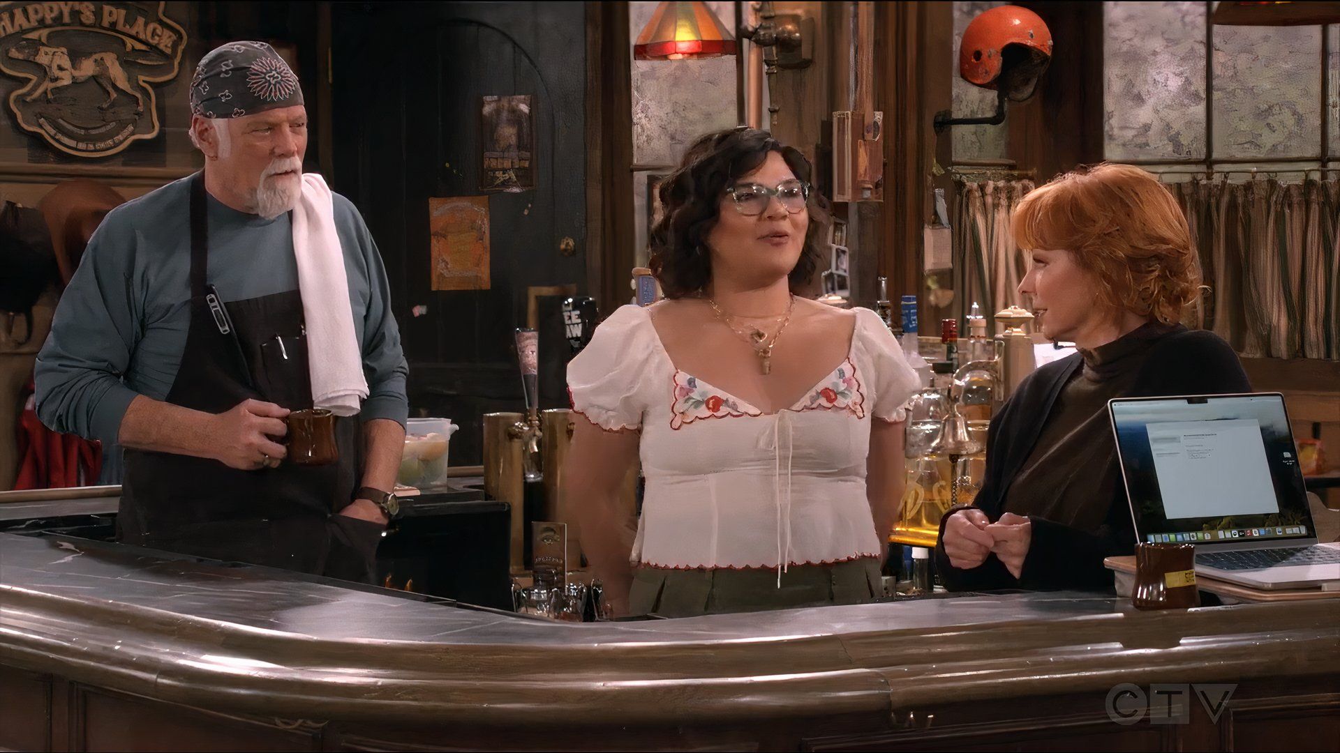 Isabella stands behind the bar smiling while Bobbie and Emmett stare at her in Happy's Place