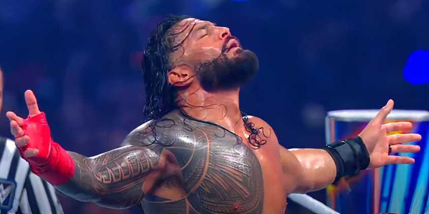 Roman Reigns standing with his arms open and eyes closed in a WWE ring
