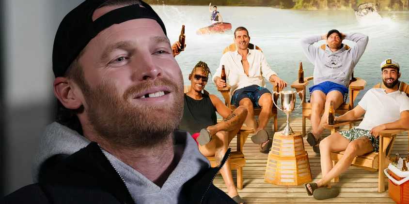 Shoresy smiles in front of a group shot of Shoresy and his teammates sitting on a dock by a lake in Shoresy season 4