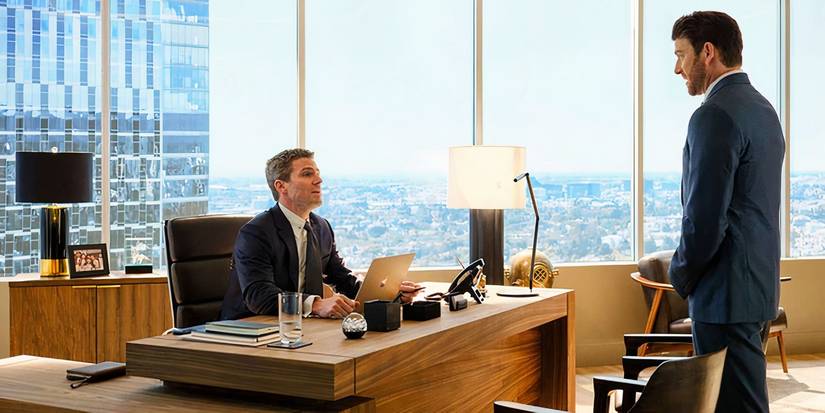 Dodson talks to Ted while standing near Ted's desk in Suits LA