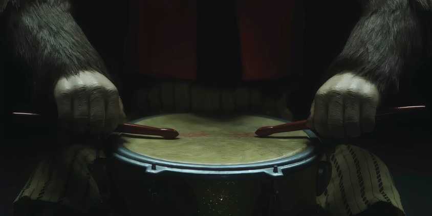 A toy monkey resting drumsticks on a drum in The Monkey