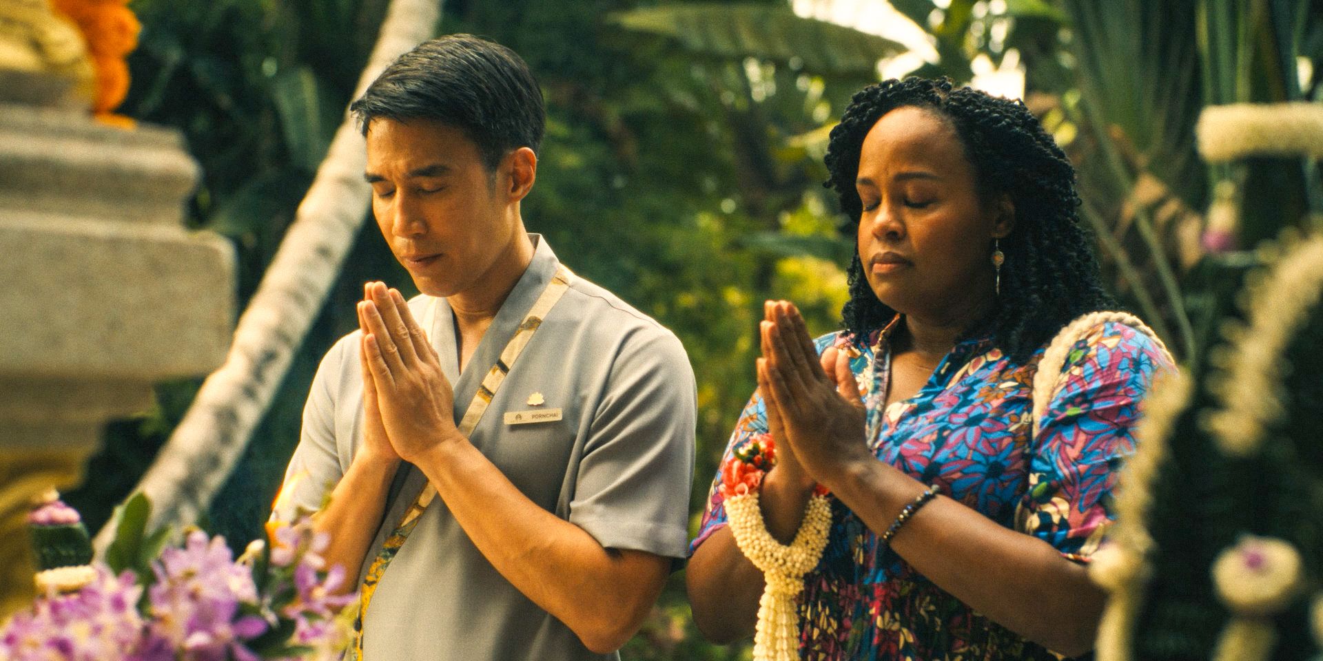 Pornchai (Dom Hetrakul) and Belinda Lindsey (Natasha Rothwell) praying to a Thai deity in The White Lotus Season 3 Ep 1