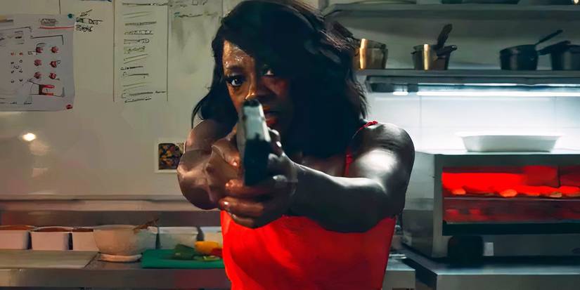 Viola Davis pointing a gun while wearing a red dress in G20