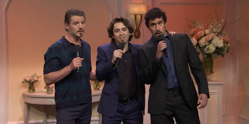 Pascal, Hernandez, and Bad Bunny stand in a group, all with mics in their end, dressed in dark blue and black wedding wear.