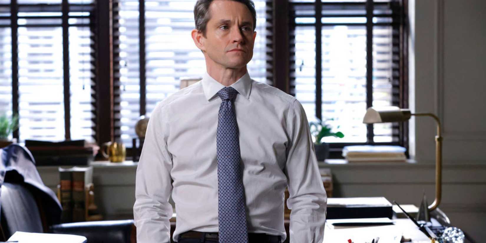 Law & Order Nolan with blue tie standing in front of his desk looking concerned