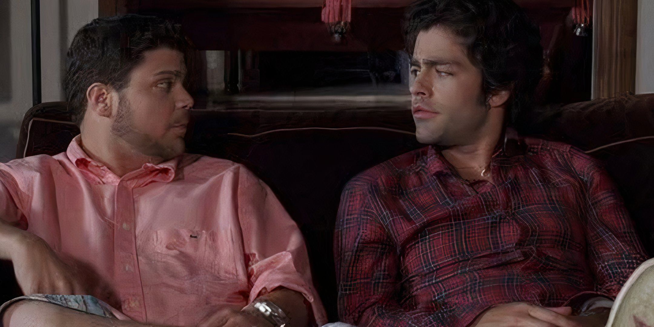 Jerry Ferrara and Adrian Grenier sit on a couch together and are looking at each other.