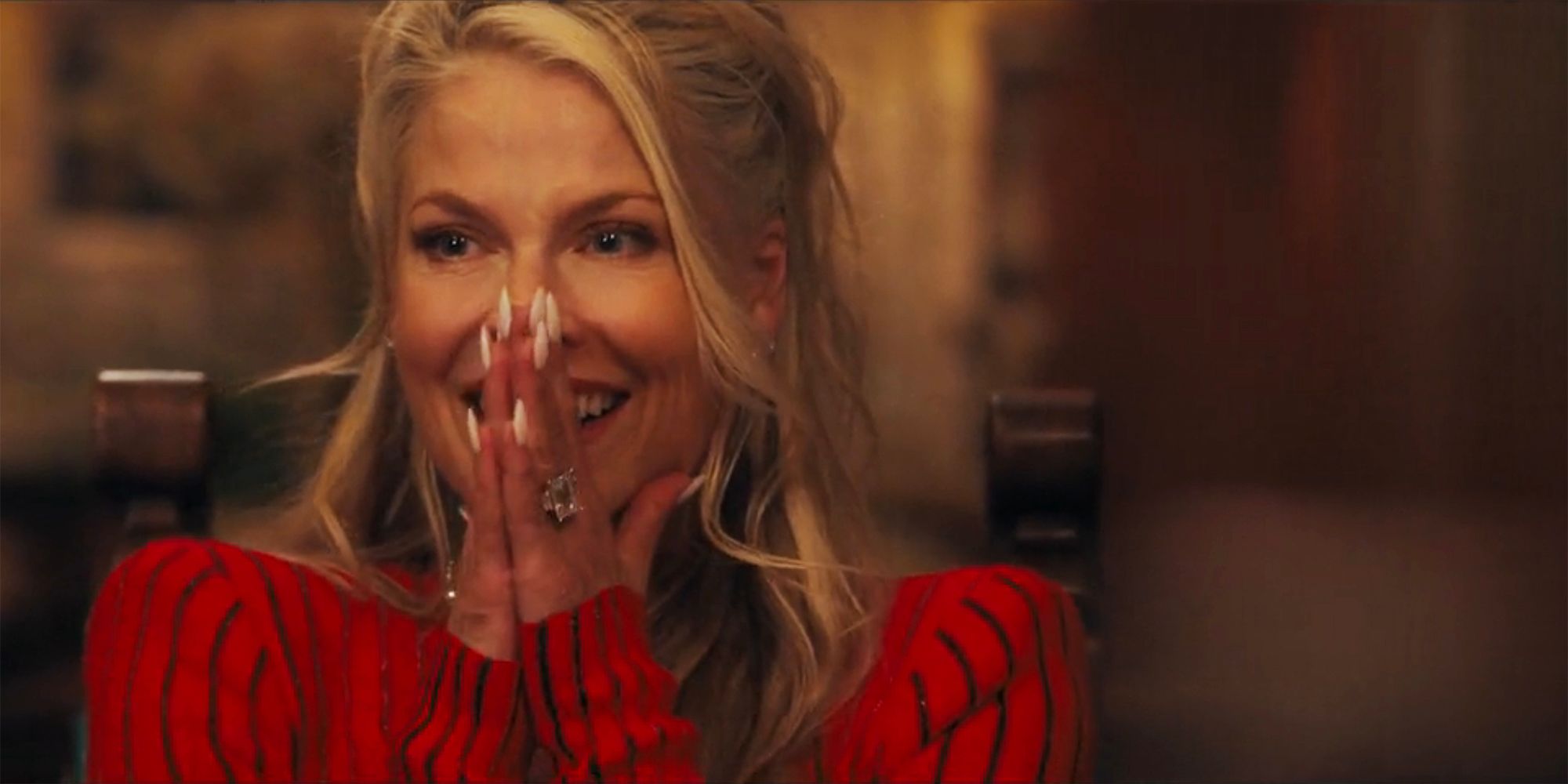 Angela with her hands clasped gleefully over her mouth in Landman