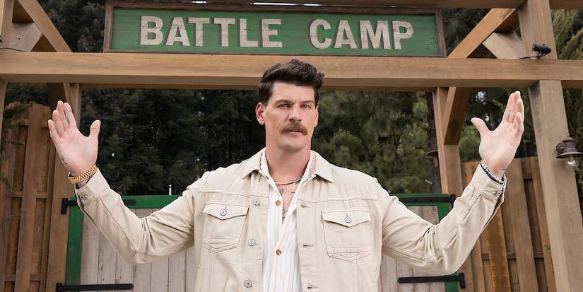Battle Camp host Taylor Lewan posing in front of a cabin