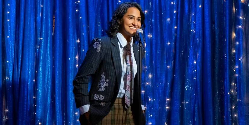 Bela (Amrit Kaur) doing stand-up on stage in The Sex Lives of College Girls season 3, episode 10.