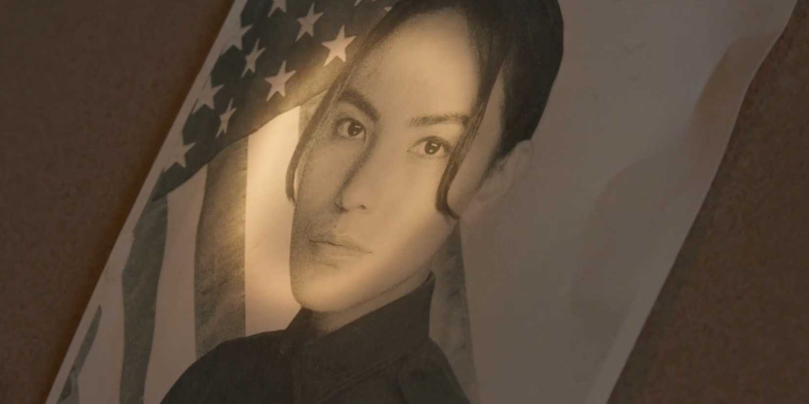 A picture of Bernadette Manuelito (Jessica Matten) in front of an American flag with a flashlight being shone on it in Dark Winds season 3, episode 3