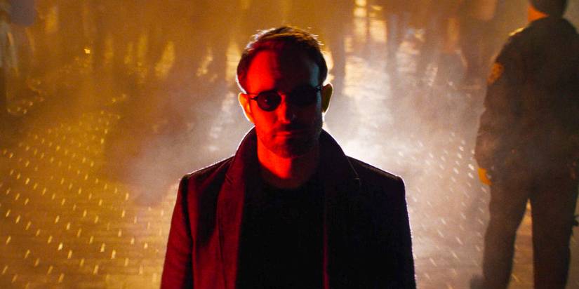 Matt Murdock (Charlie Cox) bathed in red light, with chaos unfolding behind him in Daredevil: Born Again Season 1 Ep 1