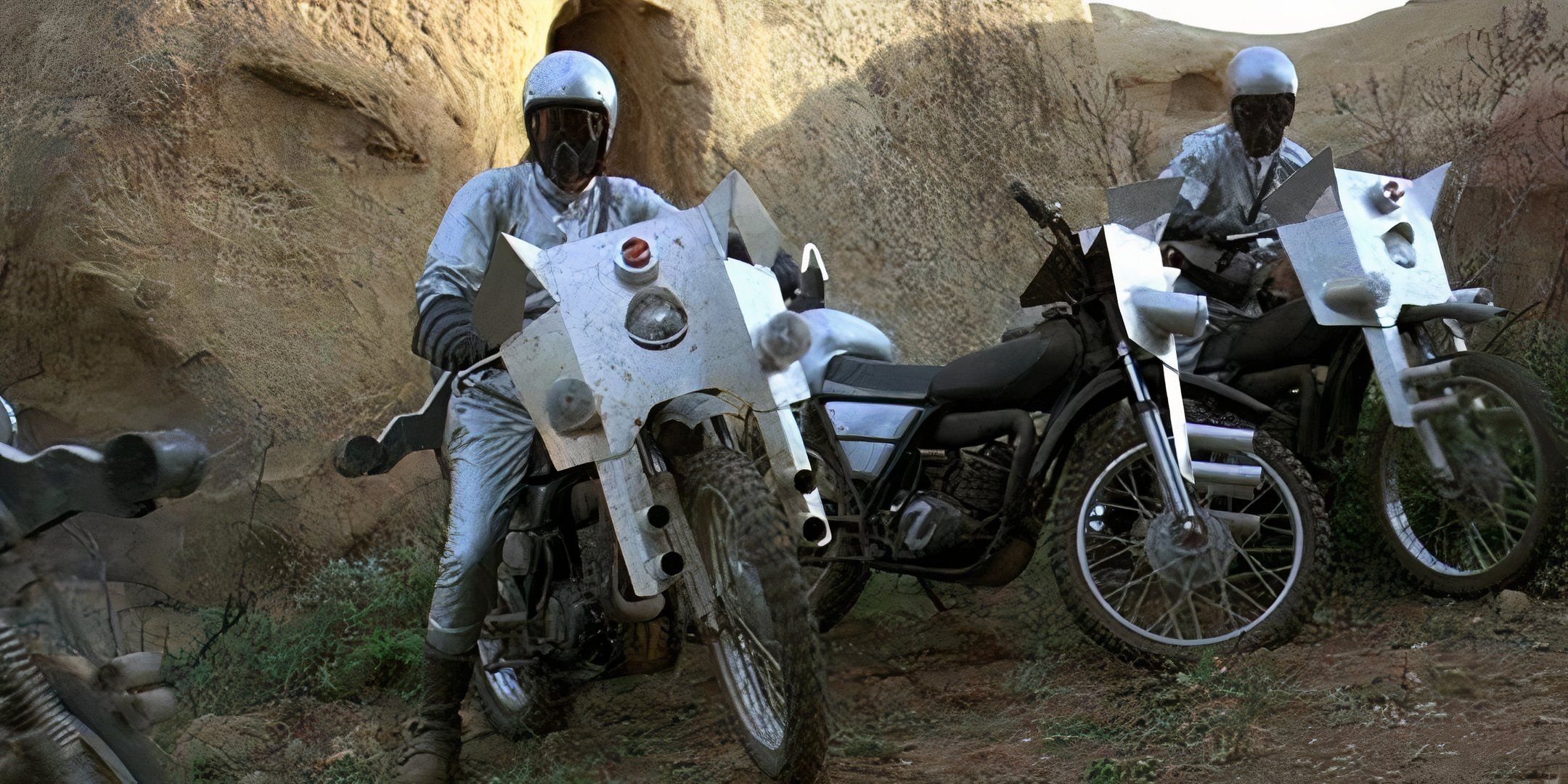 Two motorcyclists pull over on their silver, futuristic bikes. 