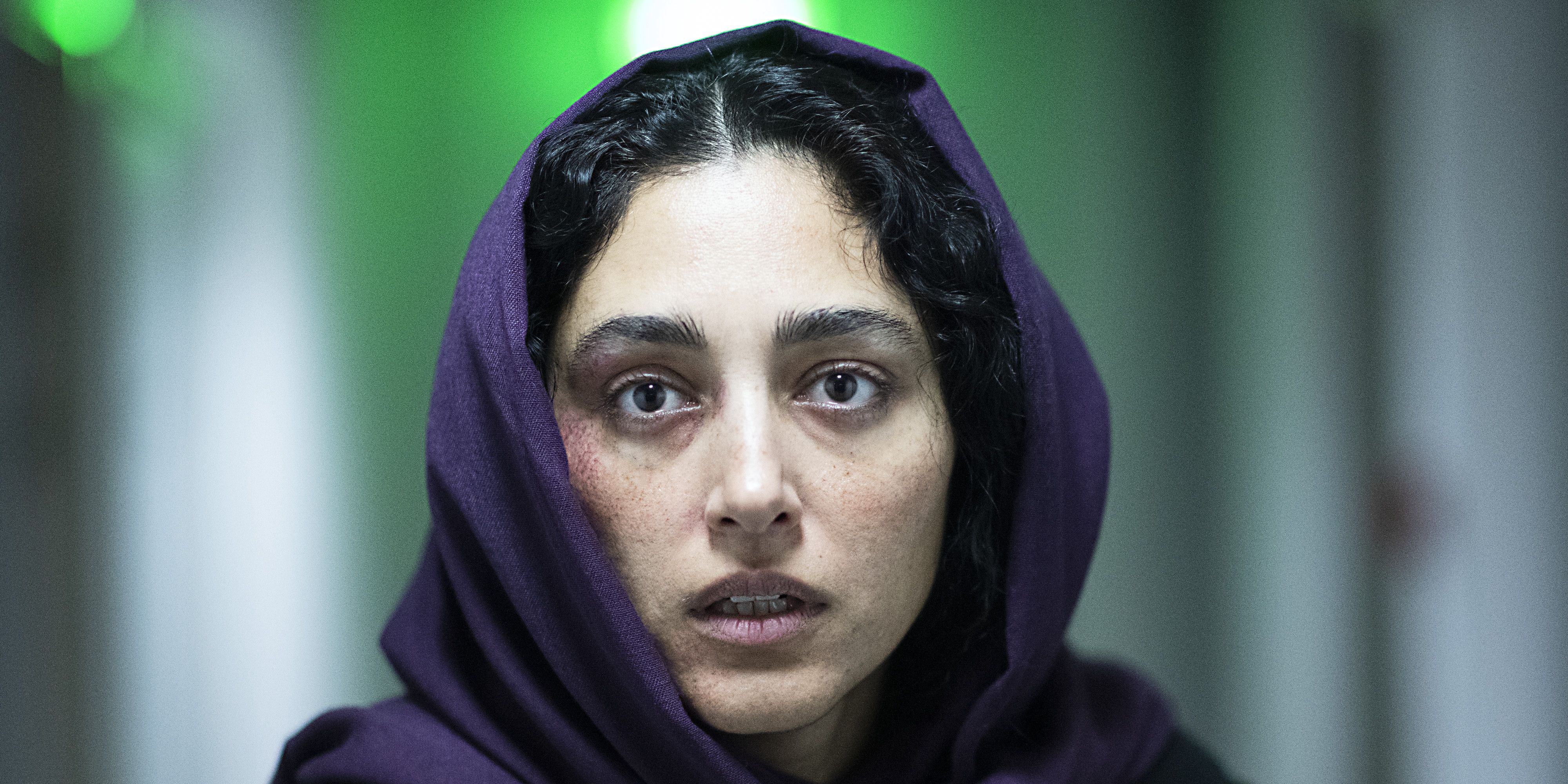 Golshifteh Farahani Hood Witch in a hallway, wearing a purple hijab 