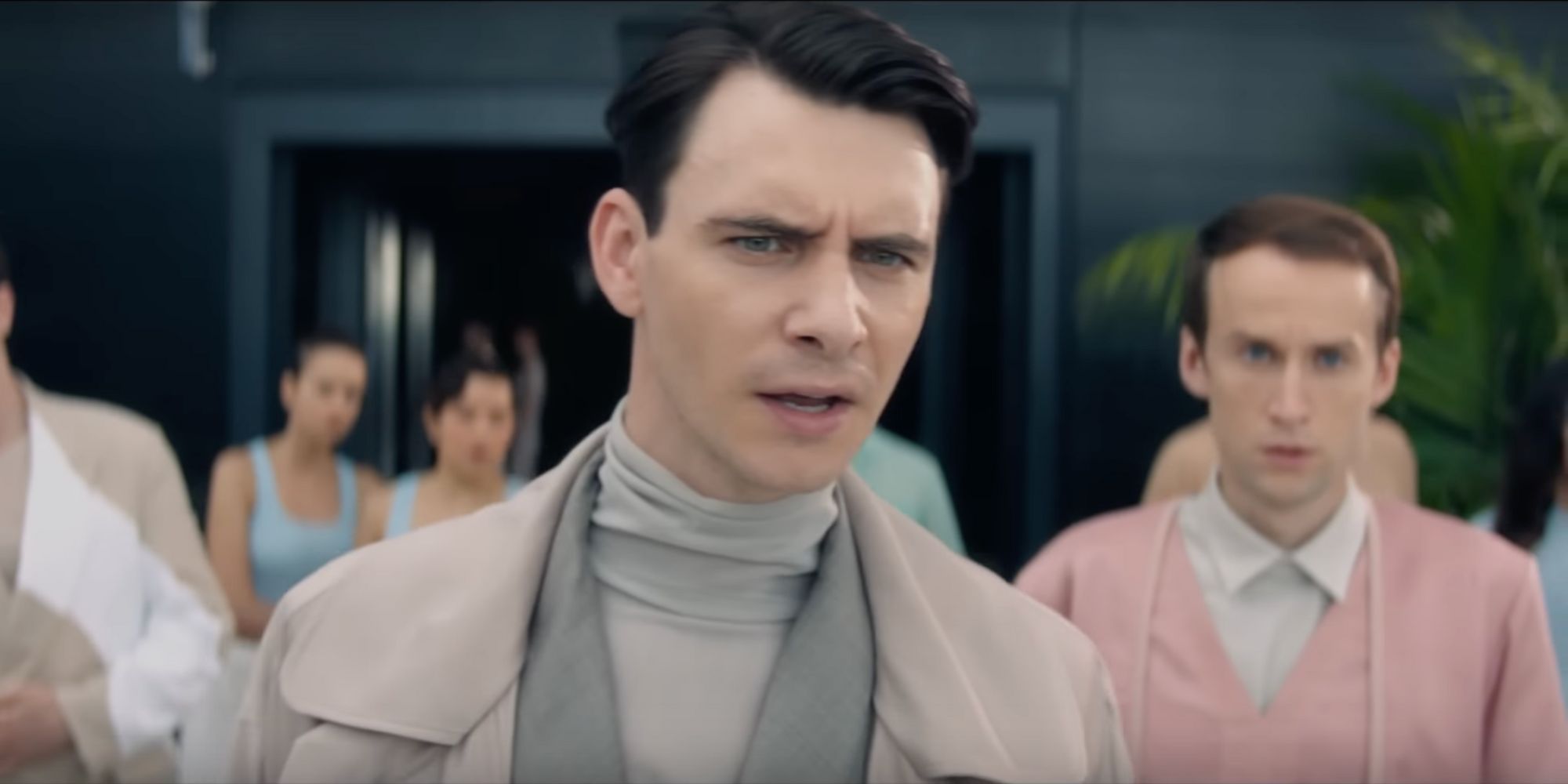 Harry Lloyd in a gray suit with furrowed brow