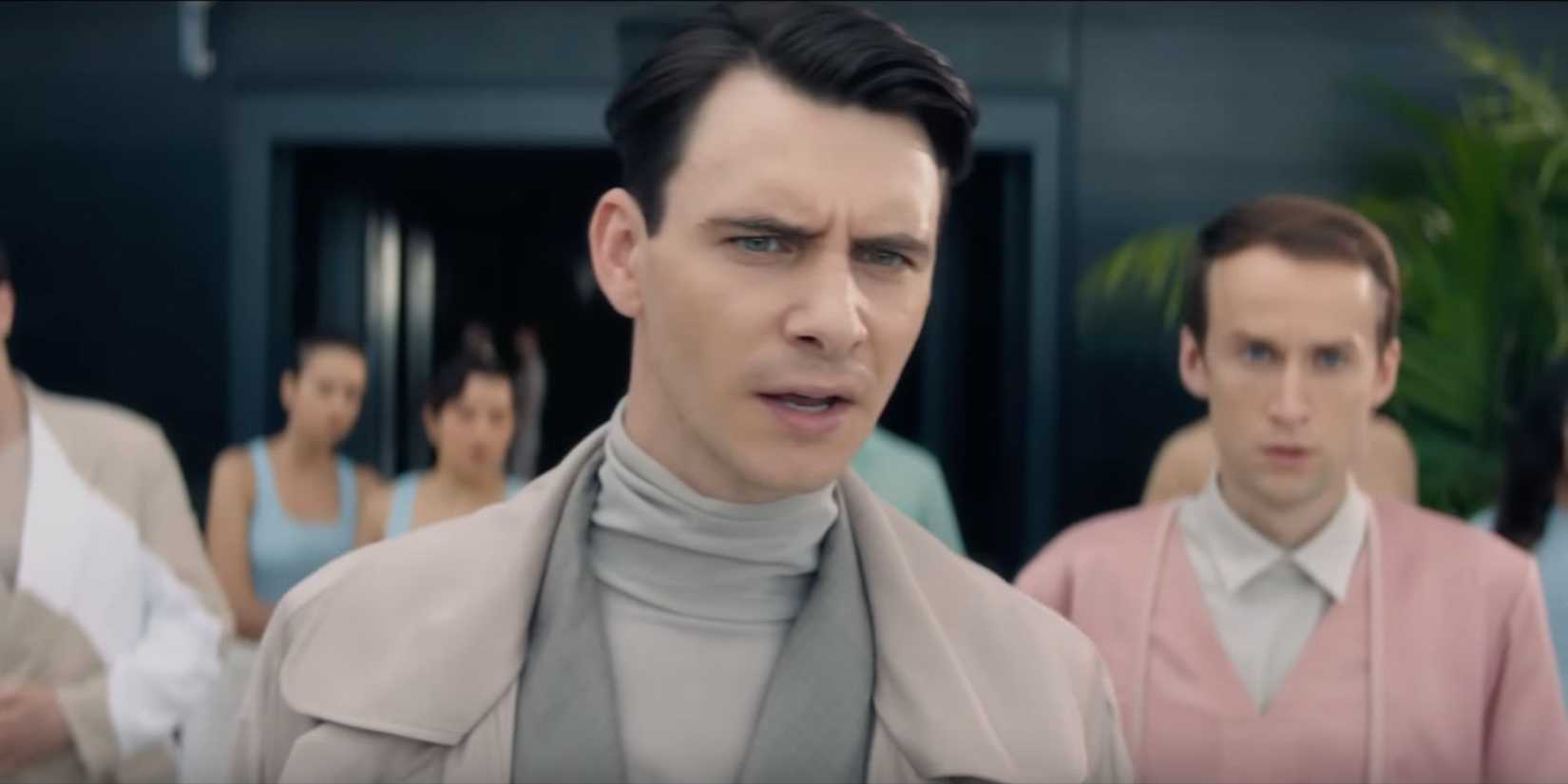 Harry Lloyd in a gray suit with furrowed brow