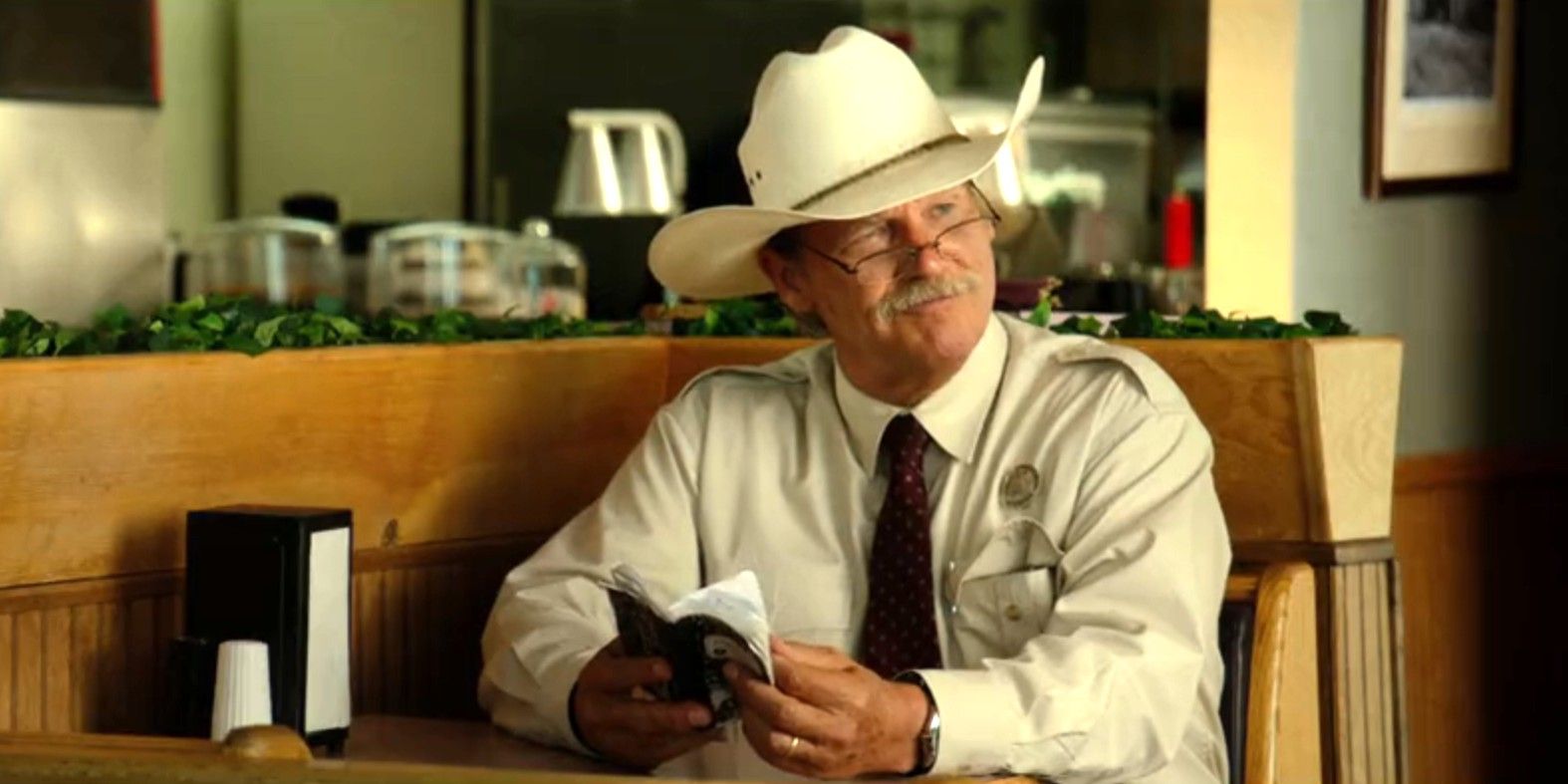 Jeff Bridges as Marcus Hamilton smiling and holding a notebook in Hell or High Water