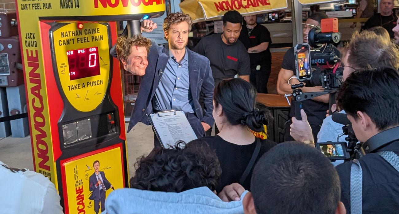 Jack Quaid Standing Outside The Alamo Drafthouse Next To A Fake Highly-Detailed Head of his Character Nathan Caine from the Film Novocaine