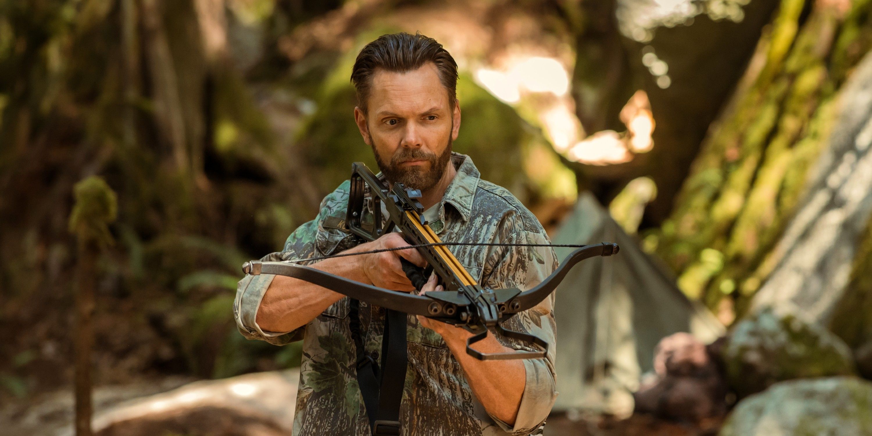 Joel McHale as Kodiak shooting a crossbow in the wilderness in Yellowjackets season 3 episode 7