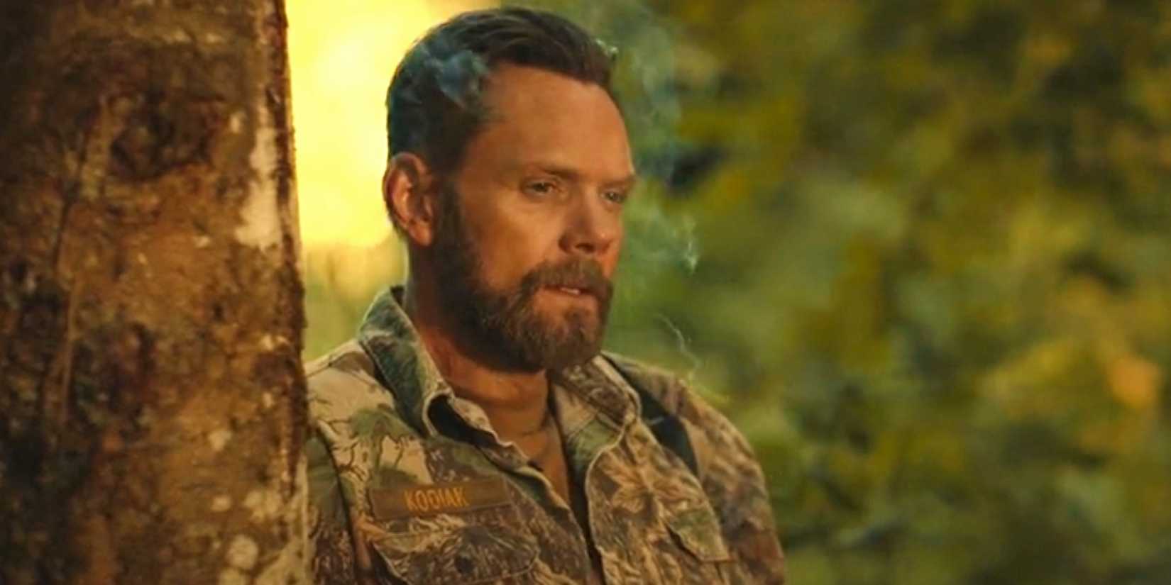 Joel McHale as Kodiak smoking next to a tree in Yellowjackets season 3 episode 7