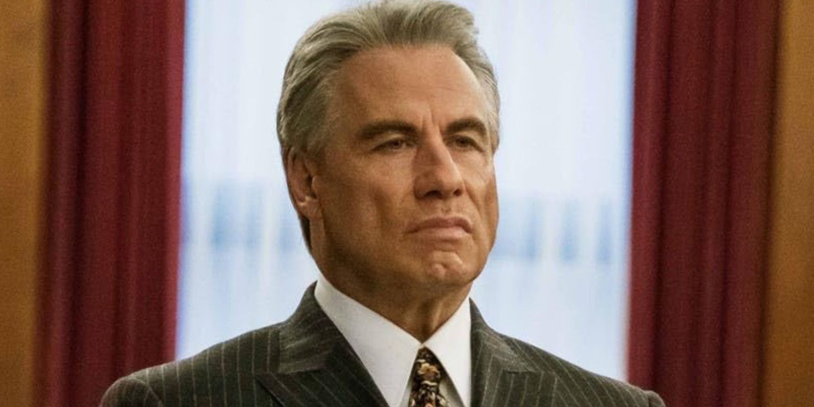 John Travolta as John Gotti looking onward with a stern expression 