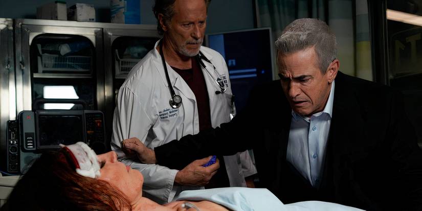 Pascal leaning over Monica's body while Archer stands nearby looking sad in Chicago Fire