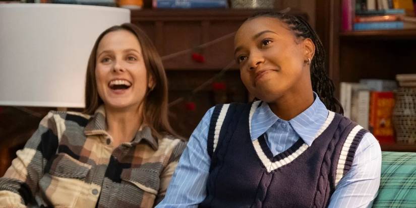 Kimberly (Pauline Chalamet) and Whitney (Alyah Chanelle Scott) laughing on the couch in The Sex Lives of College Girls season 3 episode 10.