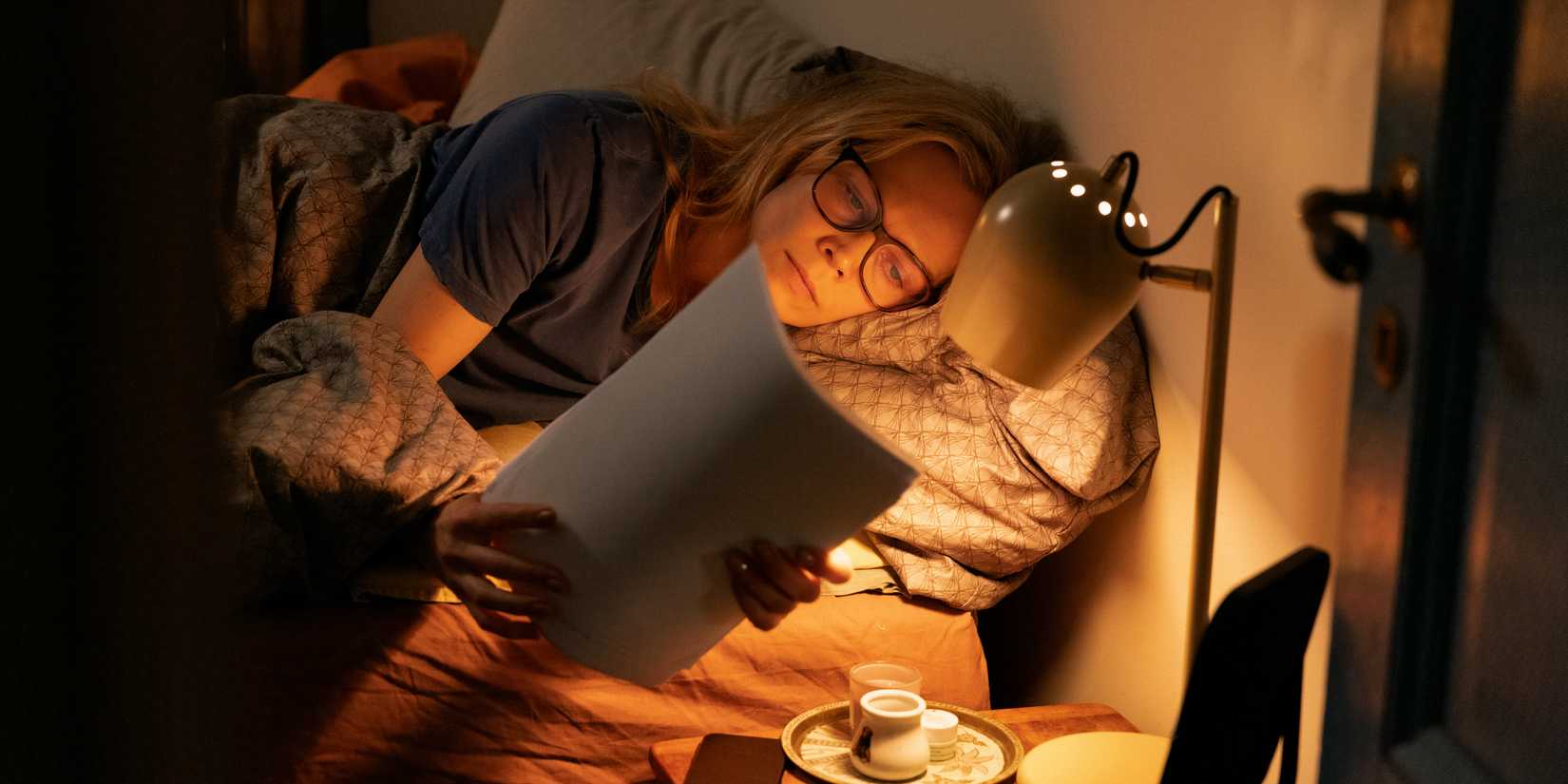 Kristin intently reading Johannes manuscript in bed in Dreams (Sex Love)