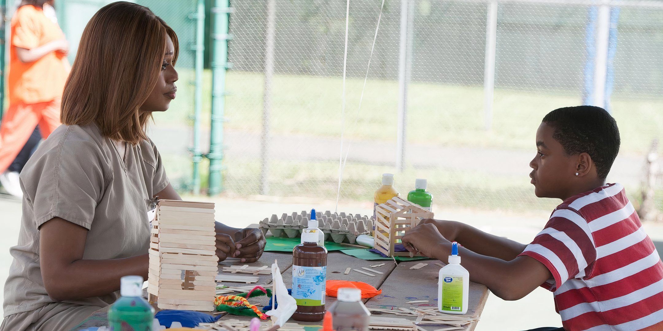 Laverne Cox and Michael Rainey Jr. sit in front of each other at a craft table.