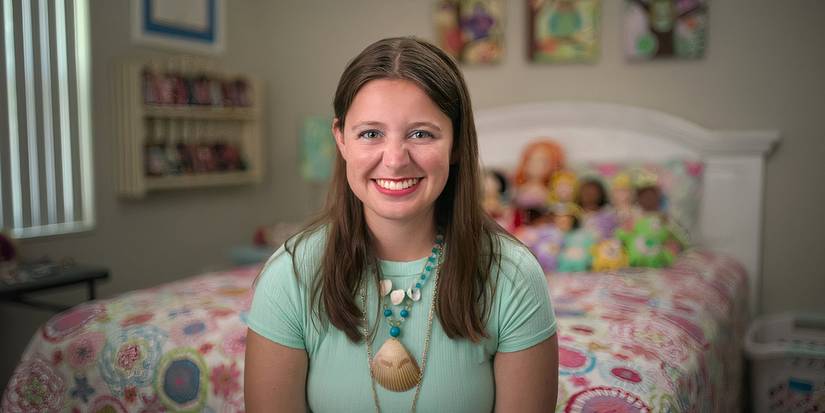 Love on the spectrum season 3 Madison Marilla is seated on her colorful bed smiling.